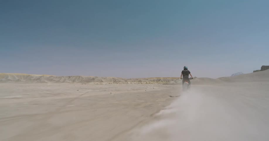 A person rides their dirt bike in the desert