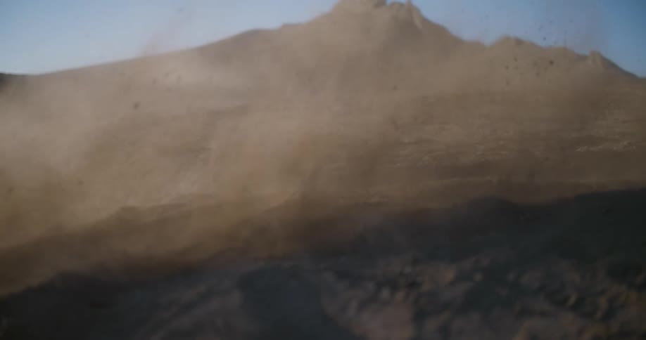 Slow motion of a person performing motocross maneuvers in an outdoor environment with dirt and dust