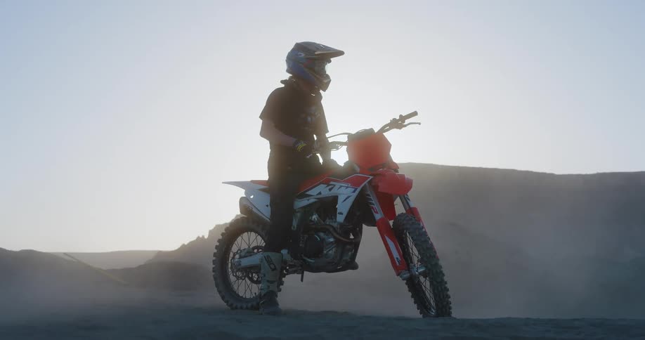 A man on his dirt bike is surrounded by a dust cloud