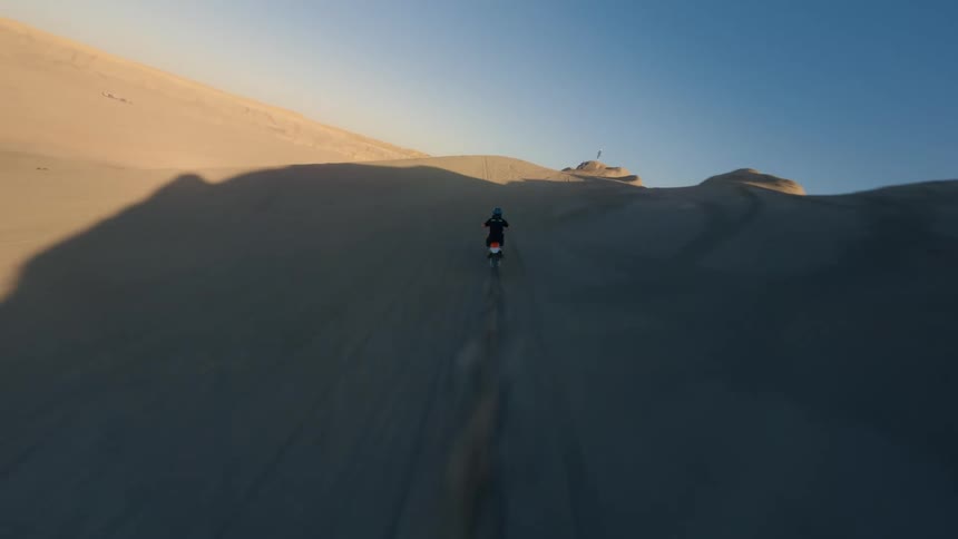 A person jumps off a dune on his dirt bike