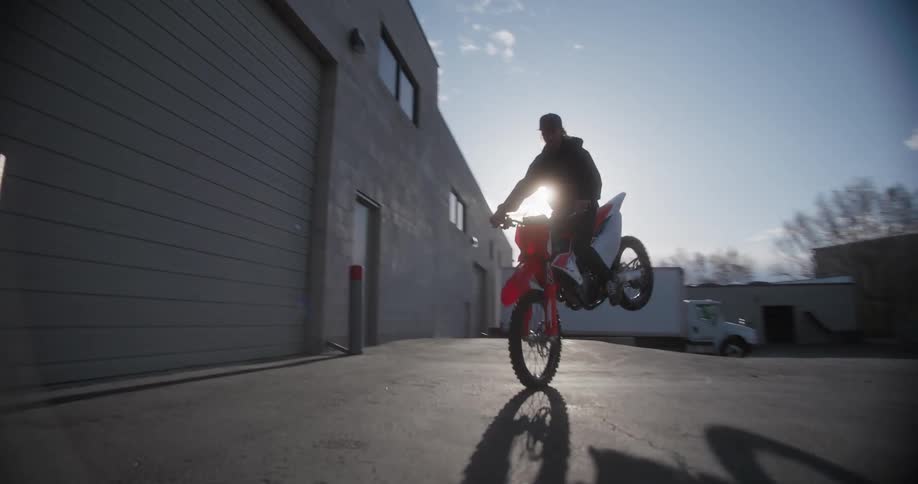 A man performing a motocross motorcycle wheelie maneuver
