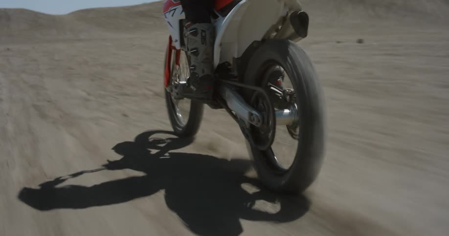 Two people riding a dirt bike on the desert