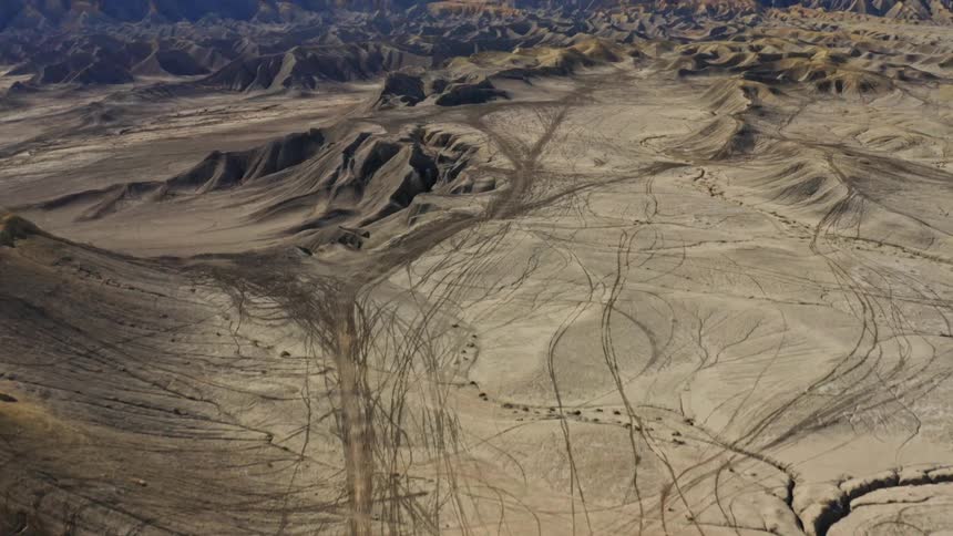 Several tire trails are marked on the sand hills and behind a huge canyon