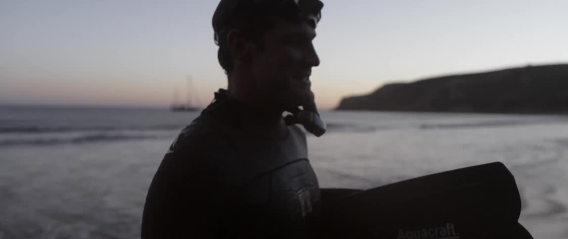 A man wearing scuba gear is talking at dawn
