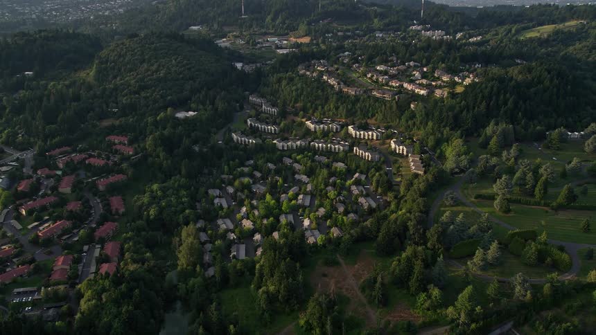 Aerial footage of a sunset over a residential apartment building in Southwest Portland Oregon with beautiful views of the surrounding hillside and lush vegetation