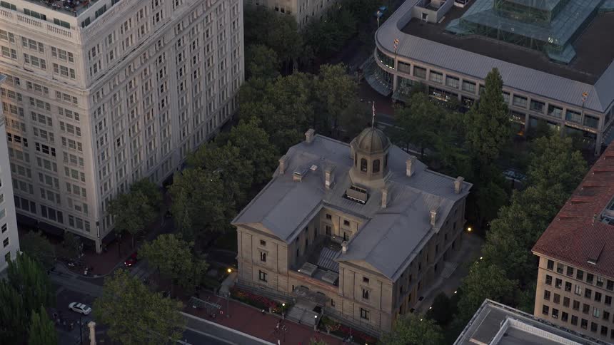 Aerial footage at sunset of flying over a skyscraper revealing the Pioneer Courthouse a federal courthouse in downtown Portland Oregon