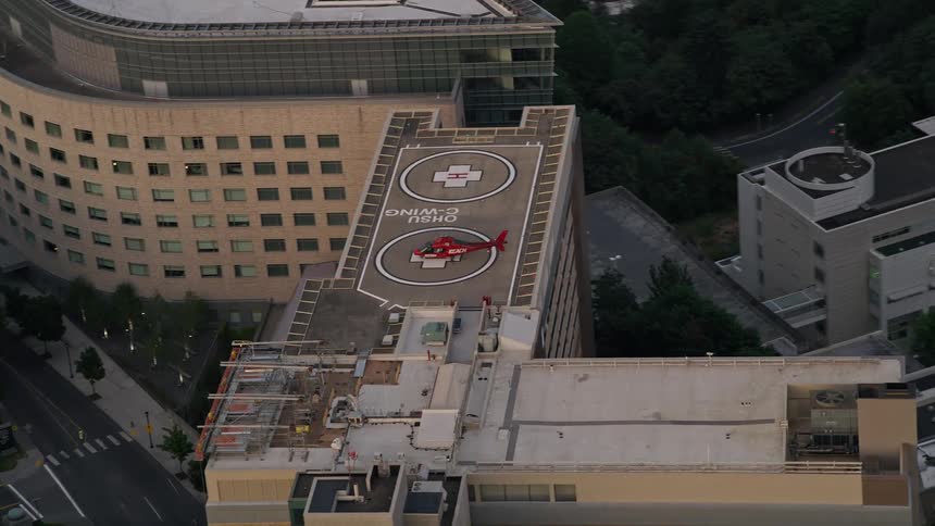 Aerial footage of a red helicopter orbiting the Oregon Health and Science University campus in Portland Oregon during twilight