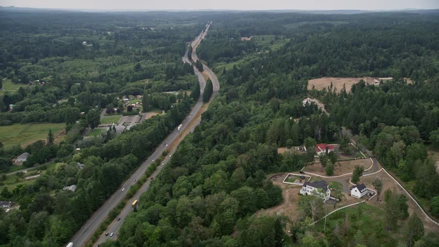 Aerial footage of cars traveling on State Route 16 past upscale homes in Olalla Washington during the summer