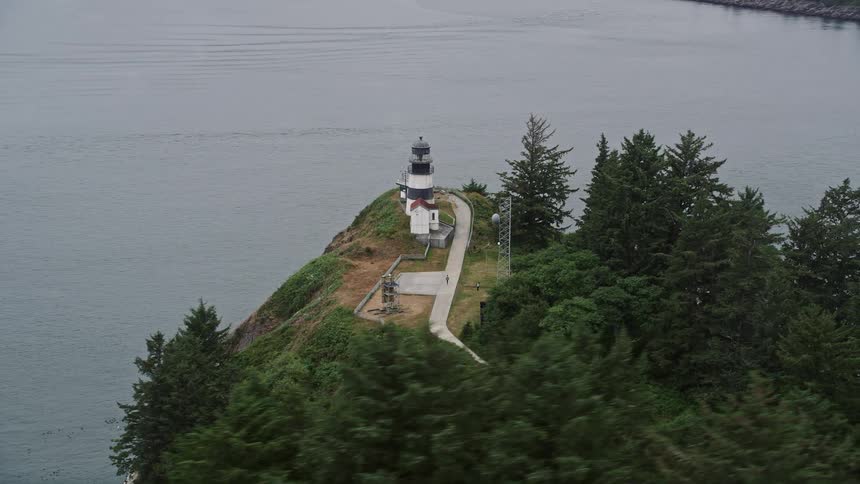 Aerial footage of Cape Disappointment Light a historic lighthouse on a hill overlooking the ocean in Washington during the summer