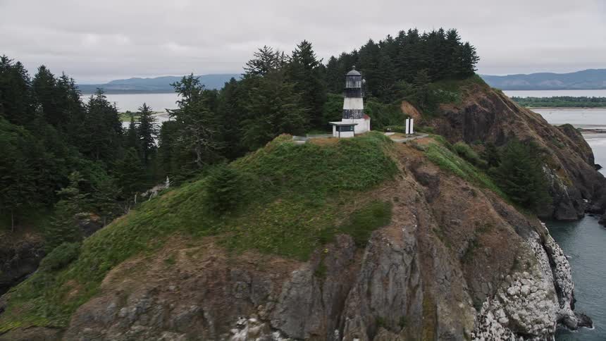 Aerial view of the Cape Disappointment Light on top of steep cliffs overlooking the Pacific Northwest coastline in Washington during the summer