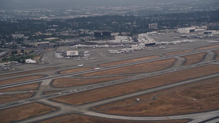 Aerial footage of a passenger airliner taking off from Seattle Tacoma International Airport on a sunny day in Washington