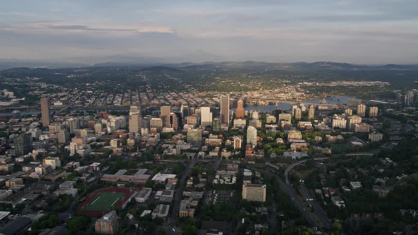 Aerial footage of downtown Portland Oregon at sunset showcasing high rise buildings by the Willamette River