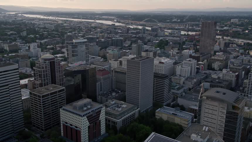 Flying over downtown Portland Oregon during sunset towards the majestic Fremont Bridge capturing the high rises skyscrapers and the beautiful Willamette River