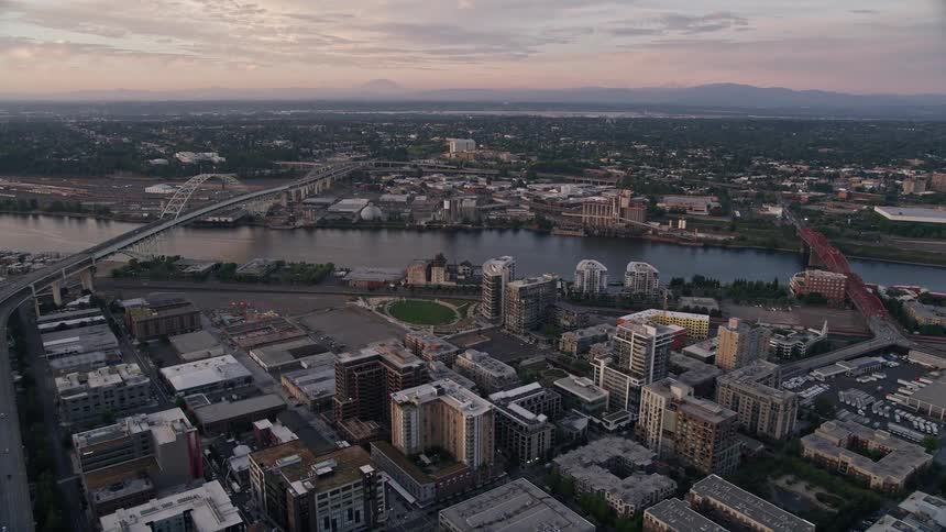 Approaching the Fremont Bridge at dusk this aerial footage showcases the stunning city skyline of downtown Portland Oregon with a beautiful sunset over the Willamette River