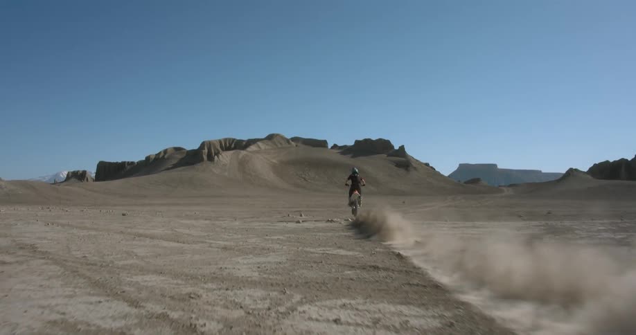 Man riding a motorcycle in a desert area on a sunny day