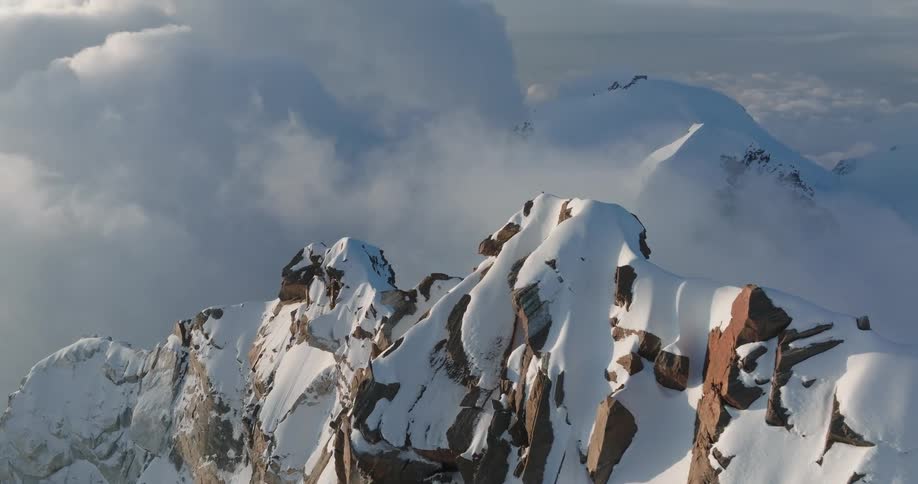 Aerial view of mountains at cloud level covered in snow