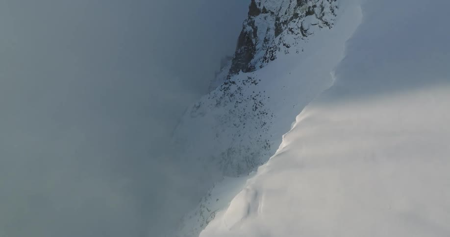 Aerial view of mountains at cloud level covered in snow