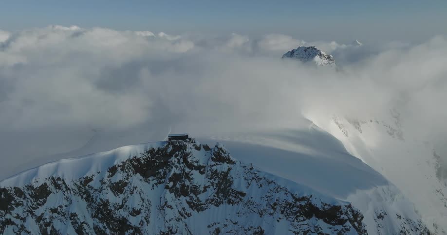 Aerial view of mountains at cloud level covered in snow