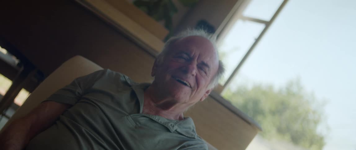 An elderly man sitting takes off a vr headset looking all happy and satisfied