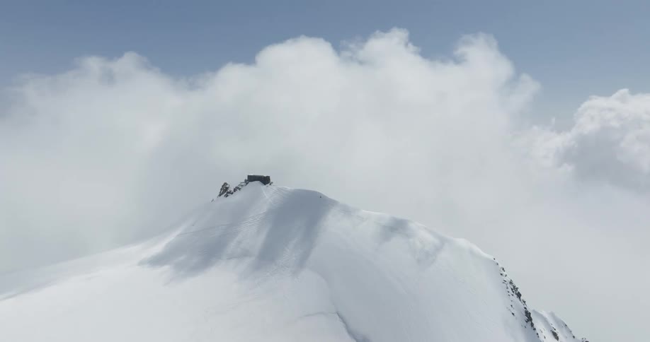 Clouds cast shadows onto snow covered mountain ridge