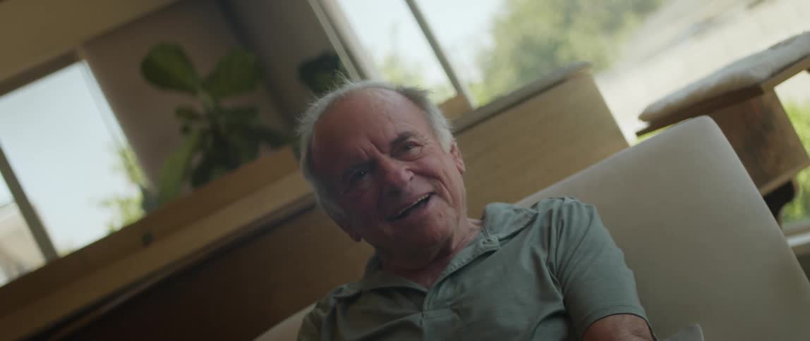 An elderly man takes off a virtual reality headset and catches his breath while smiling