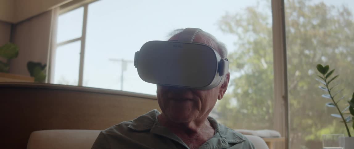 An elderly man wearing a vr headset while seating in the living room