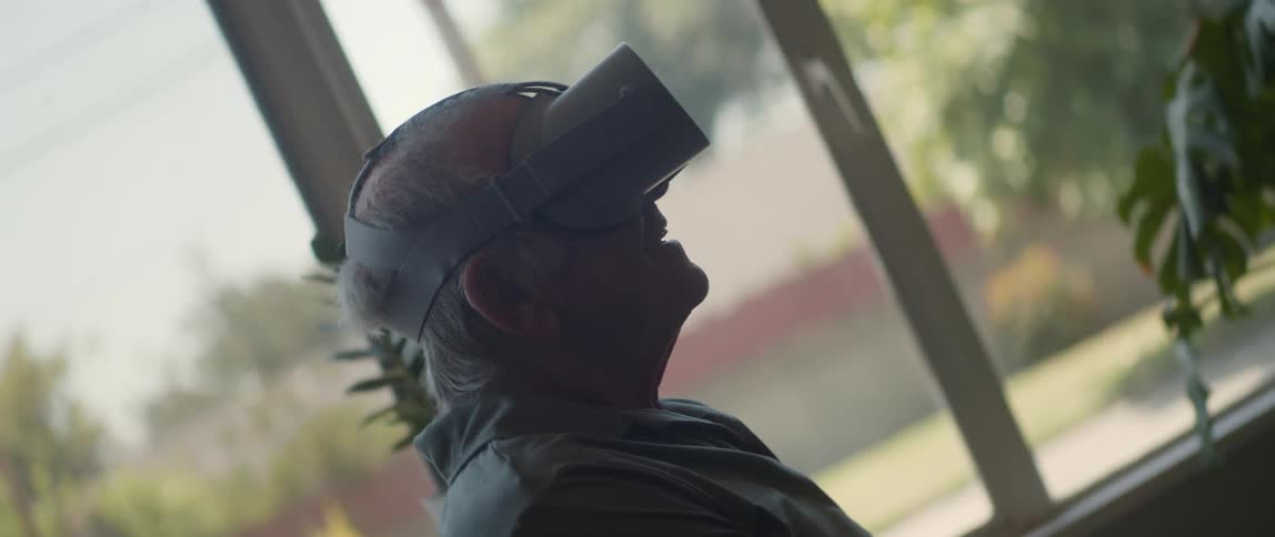 An old man sitting with a virtual reality headset on his head
