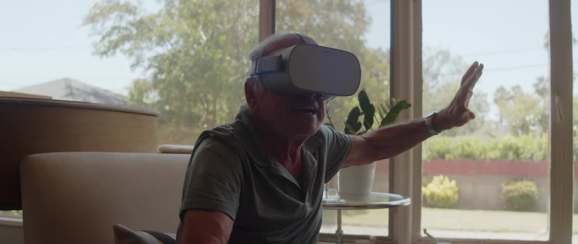 Elderly person using virtual reality glasses and moving their arms as if they were fighting with a sword