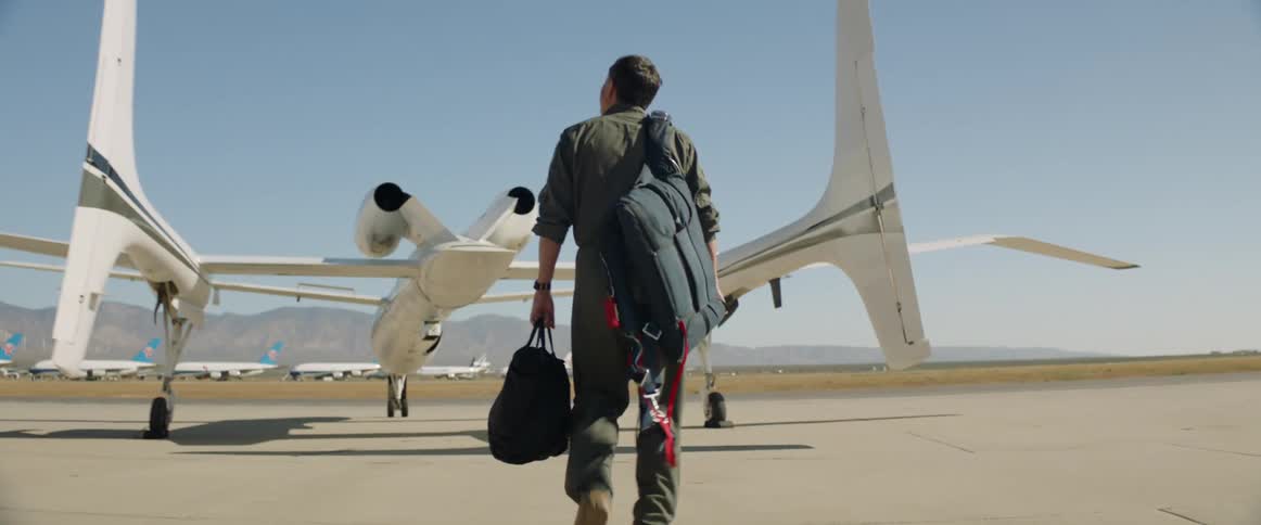 Pilot walking to a plane while carrying bags on a sunny day