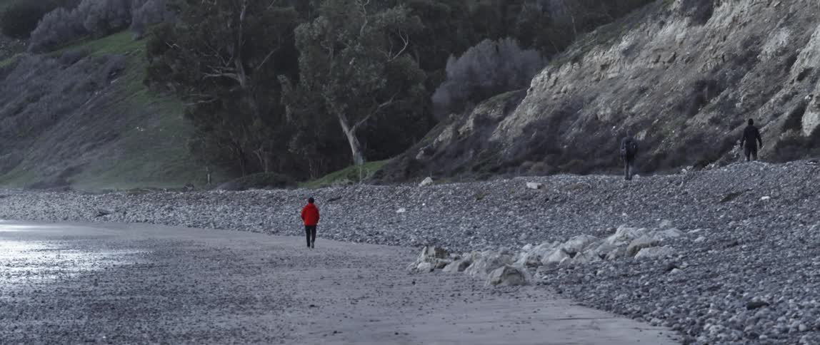A man is walking along the beach ahead