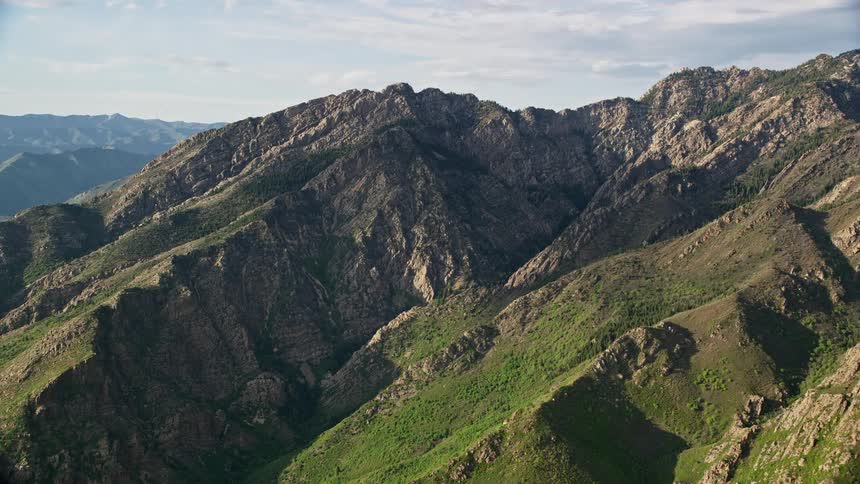 Aerial footage of Mount Olympus in the Wasatch Range Utah showcasing the breathtaking mountain peaks and partly cloudy skies during a summer day
