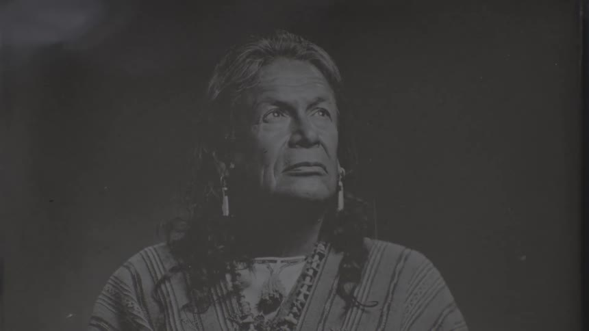 Closeup of a black and white photograph with liquid poured over an indian man