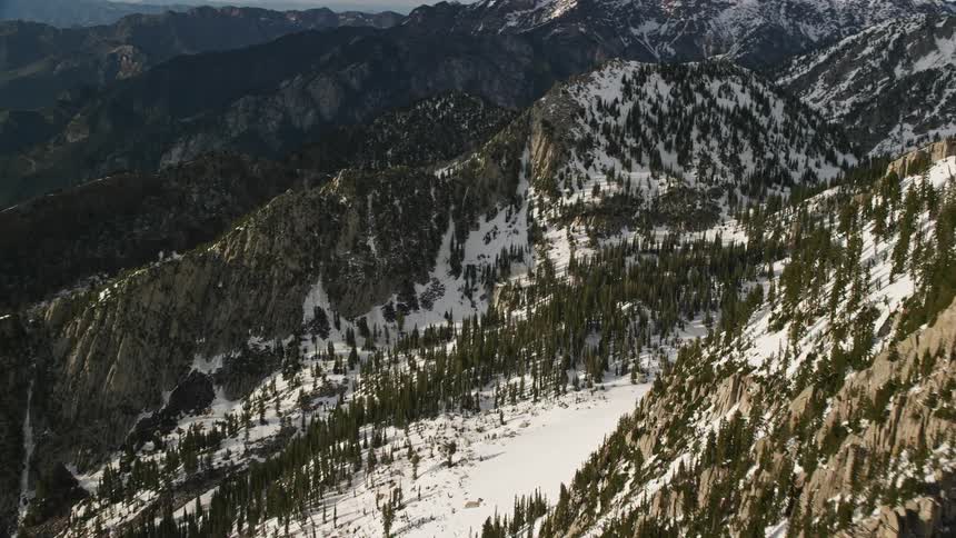 Panoramic aerial view of snowy Lone Peak in the Wasatch Range Utah with partly cloudy skies and winter season ambiance