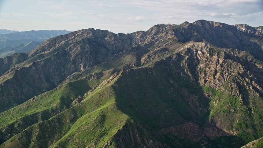 Aerial footage of Mount Olympus in the Wasatch Range Utah showcasing the scenic mountain peaks and partially cloudy skies during summer