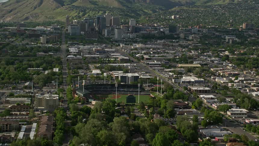 Aerial footage of Spring Mobile Ballpark and Downtown Salt Lake City Utah during summer showcasing a baseball field in the middle of the city
