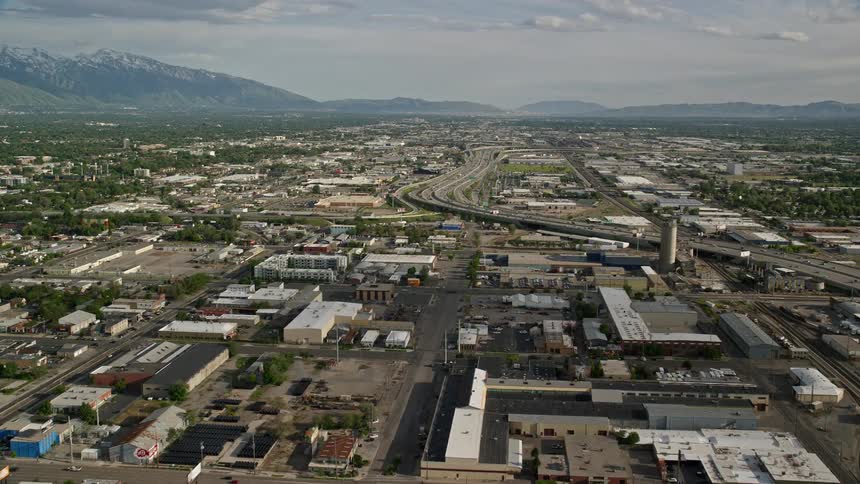 Aerial footage of Salt Lake City Utah showing streets buildings Interstate 15 and a mountain range on the horizon during a sunny day in summer