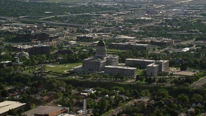 Aerial footage captures the Utah State Capitol Temple Square and downtown buildings in Salt Lake City Utah with sunny weather and a panoramic view of the cityscape showcasing the government building and Mormon landmarks