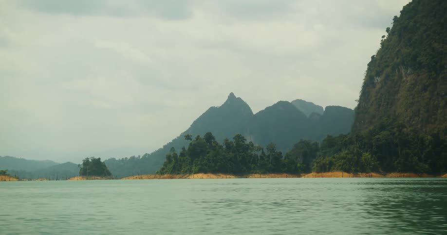 Ocean waters meeting land with dense forests and mountains in the distance