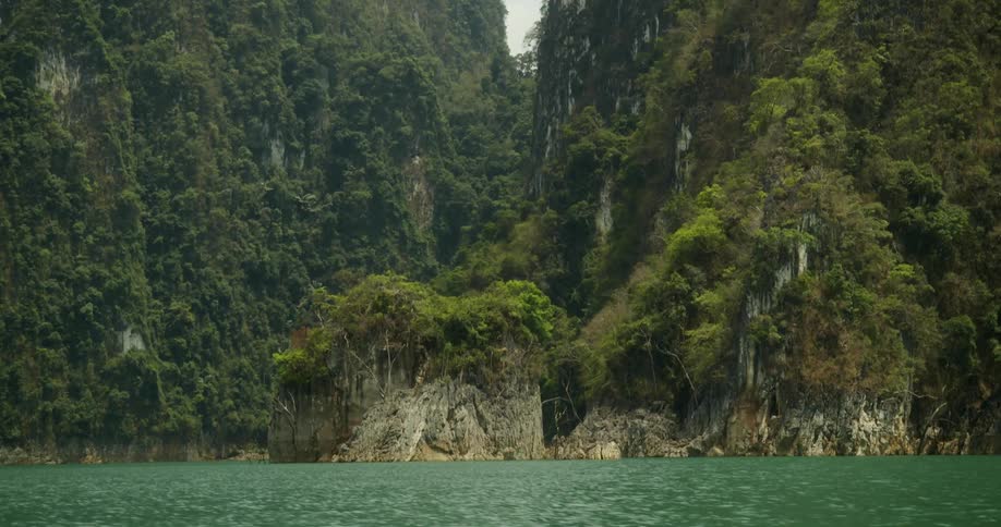 Water meeting land with mountain ridges covered in vegetation during the day