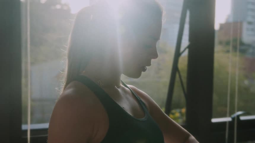 A woman in a sports bra looks at her wristwatch