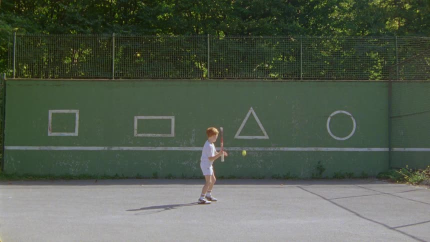 A child is playing tennis by himself