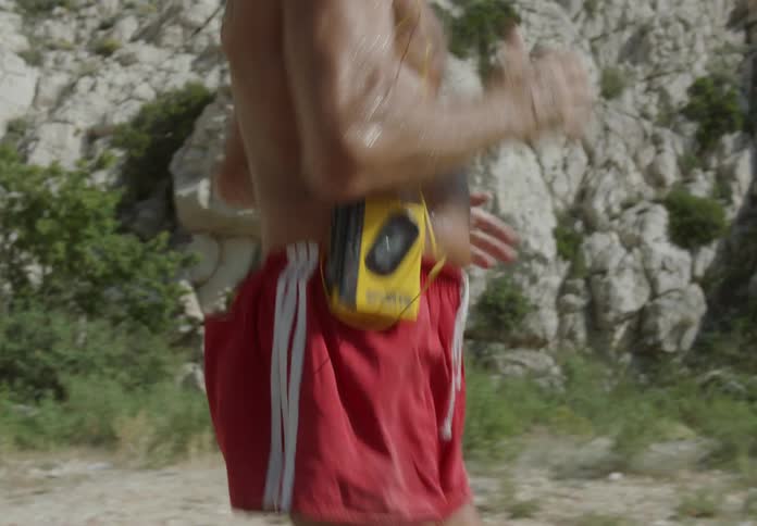 An old man jogging shirtless while wearing a walkman