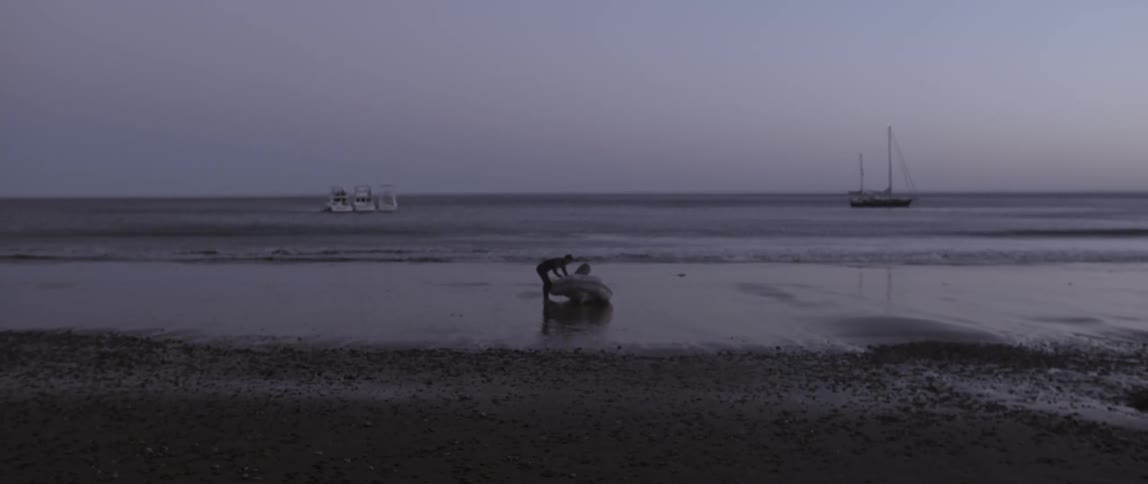 A man is putting items in a raft on the beach