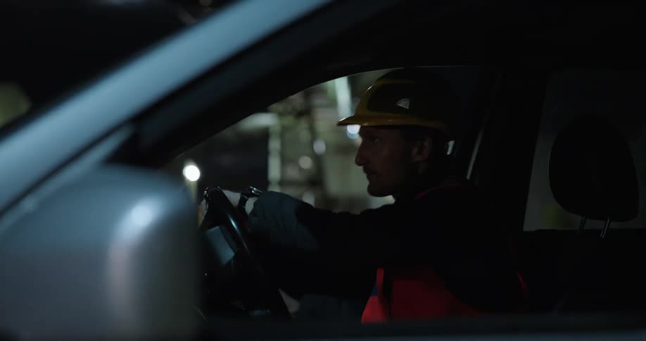 A construction worker puts on his helmet before getting out of his truck