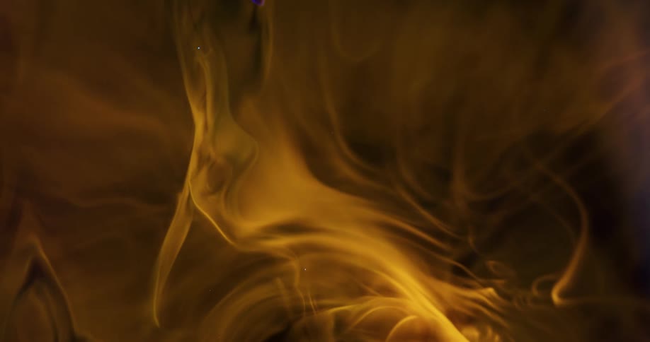 Yellow tinted smoke whirling slowly around in a dark space
