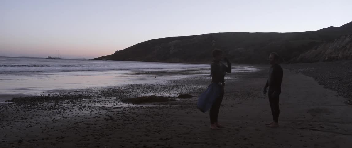 Two people are on the sand of a beach