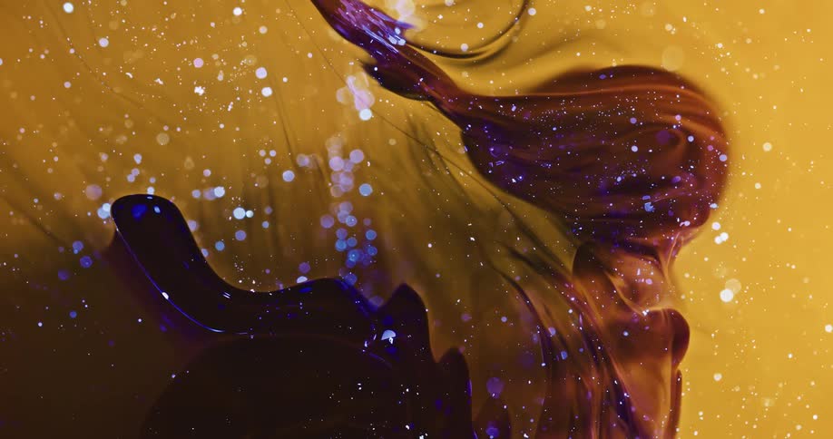 Blue glitter floats over swirling yellow and dark red ink