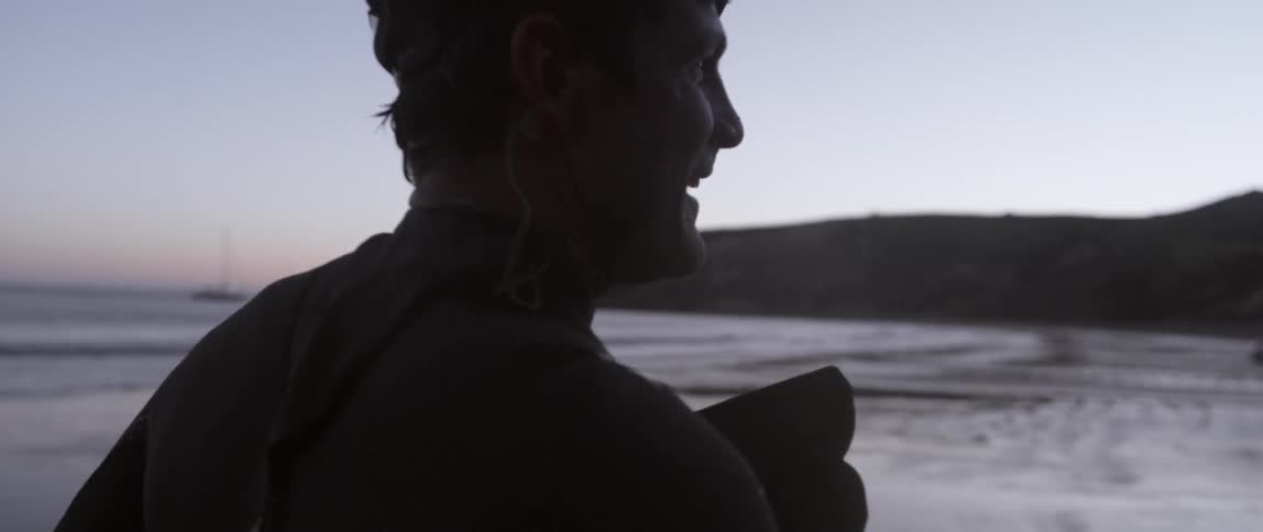 A man is walking on a beach at sunset