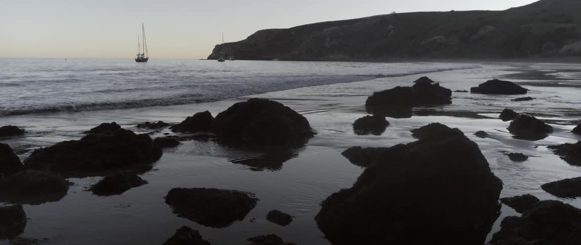 Waves crash against the rocks and sand on the shore