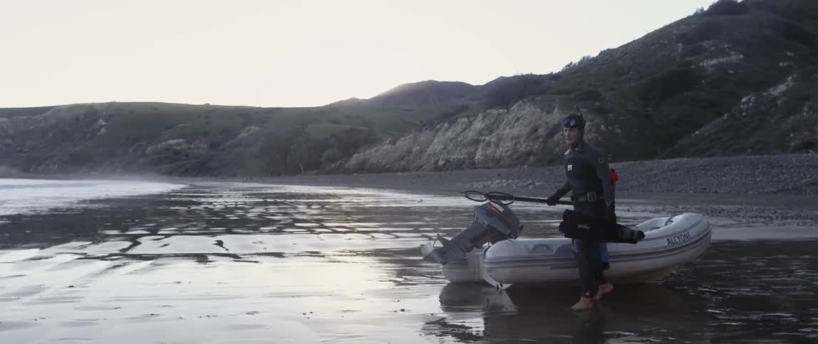 A man in scuba gear walks from a raft talking